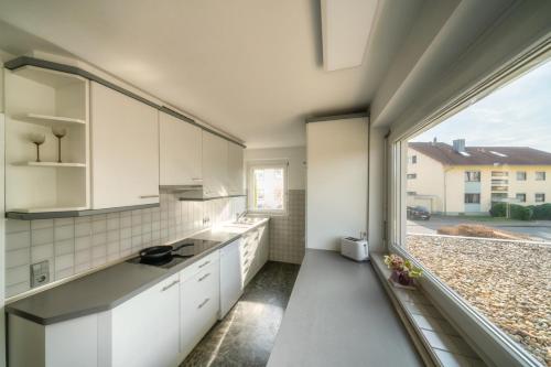 a kitchen with white cabinets and a large window at Homebase bei Freiburg in March