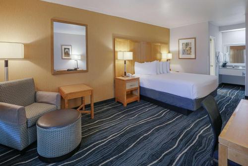 Habitación de hotel con cama y silla en Ramada by Wyndham Costa Mesa/Newport Beach, en Costa Mesa