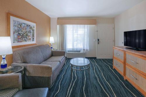 a living room with a couch and a flat screen tv at Ramada by Wyndham Costa Mesa/Newport Beach in Costa Mesa