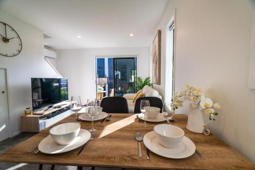 a dining room with a table with plates and wine glasses at King bed on Hagley Park corner in the CBD in Christchurch