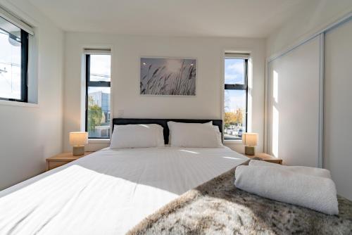 a bedroom with a large white bed with windows at King bed on Hagley Park corner in the CBD in Christchurch