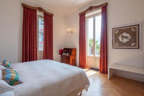 a bedroom with a white bed and red curtains at Villa by @ Home Hotel Locarno in Locarno