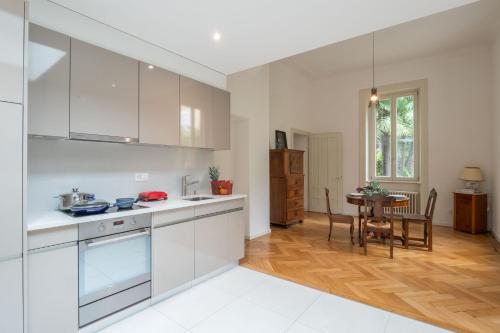 a kitchen with white cabinets and a table in it at Villa by @ Home Hotel Locarno in Locarno