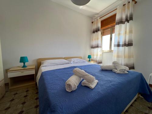 een slaapkamer met een blauw bed en handdoeken bij Residence Atlante in Leporano