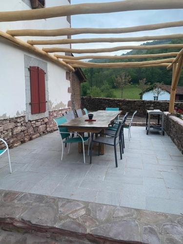 a wooden table and chairs on a patio at chambres d'hôtes Etche Iza in Hosta
