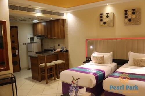 a hotel room with two beds and a kitchen at Pearl Executive Hotel Apartments in Dubai