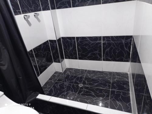 a black and white shower with a black tile floor at Casa del Virrey Hospedaje in Jauja