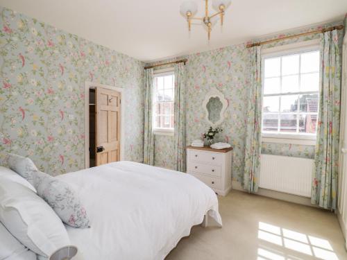 una camera da letto con un letto bianco e carta da parati floreale di 4 The Old Council House a Shipston-on-Stour
