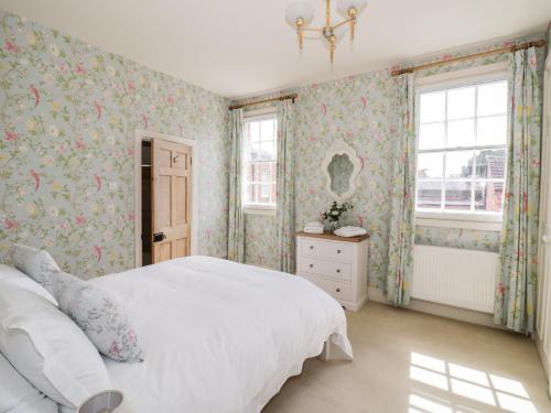 1 Schlafzimmer mit einem weißen Bett und Blumentapeten in der Unterkunft 4 The Old Council House in Shipston on Stour