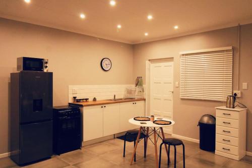 a kitchen with a small table and a black refrigerator at Clifton Home in Richards Bay