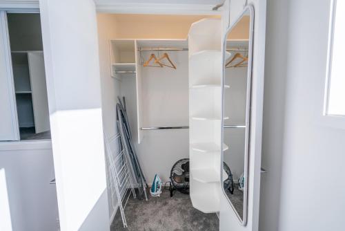 a closet with white shelves and a mirror at King bed on Hagley Park corner in the CBD in Christchurch