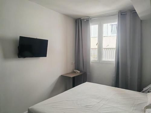 - une chambre avec un lit et une télévision murale dans l'établissement HOSTAL GOLDEN 21***, à Madrid
