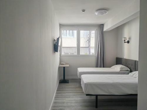 2 camas en una habitación con ventana en HOSTAL GOLDEN 21***, en Madrid