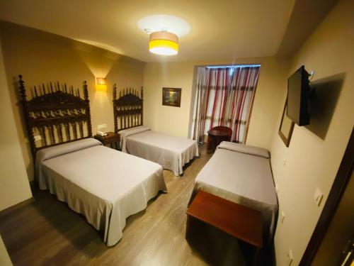 a hotel room with two beds and a television at Hotel Gran Casona de Sanabria in Puebla de Sanabria