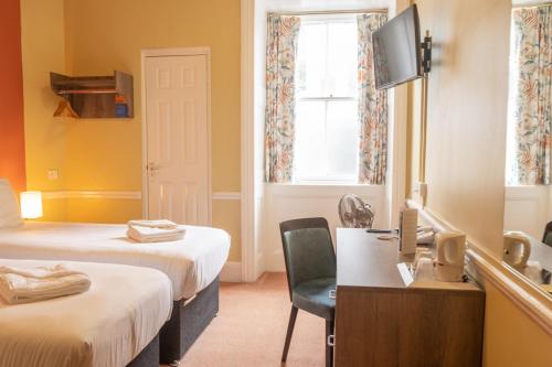 a hotel room with two beds and a desk and a tv at The Cosener's House in Abingdon