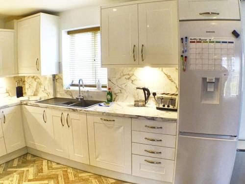 uma cozinha com armários brancos e um frigorífico branco em Pete's Place - 97a Grantley Gardens - Plymouth Devon em Plymouth