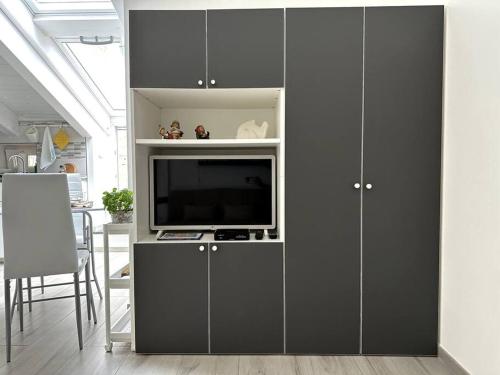 a living room with a entertainment center with a tv at The sweet attic room - De Vivo Realty Meta di Sorrento in Meta