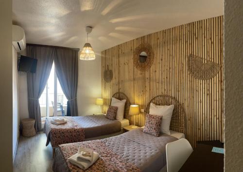une chambre d'hôtel avec deux lits et un canapé dans l'établissement Hotel Alcyon, à Valras-Plage