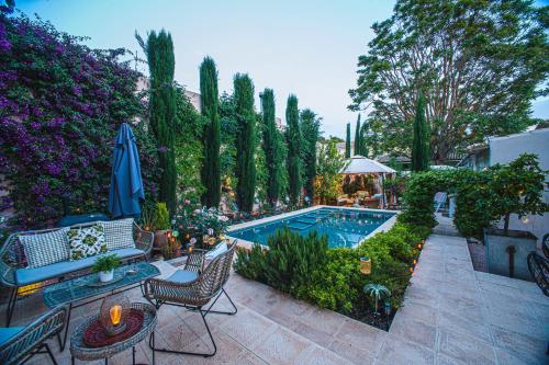 a backyard with a swimming pool and a patio with chairs and an umbrella at Boutique B&B Suite at Casa Grande in Pinoso
