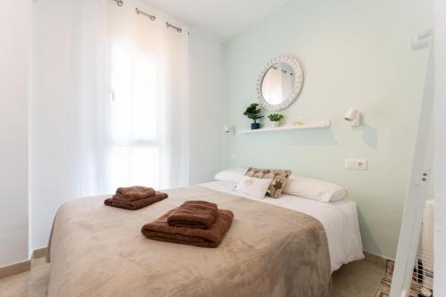 een witte slaapkamer met een bed met handdoeken erop bij MalagaSuite Sun & Sea Fuengirola in San Francisco