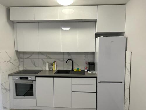 a white kitchen with a sink and a refrigerator at Kršić Apartman in Baošići