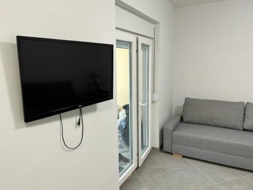 a flat screen tv hanging on a wall in a living room at Kršić Apartman in Baošići