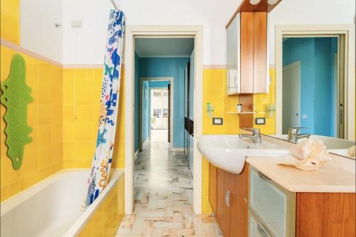 a bathroom with yellow walls and a sink and a tub at Affittacamere Al Ducale in Urbino
