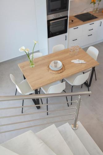a kitchen with a wooden table and white chairs at Heavenly Heights Villas By KB Hospitality in Évyiros