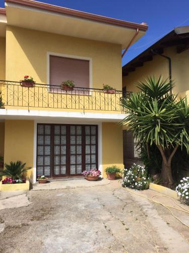 a yellow house with potted plants and a balcony at B&B ANNA in Piscinas