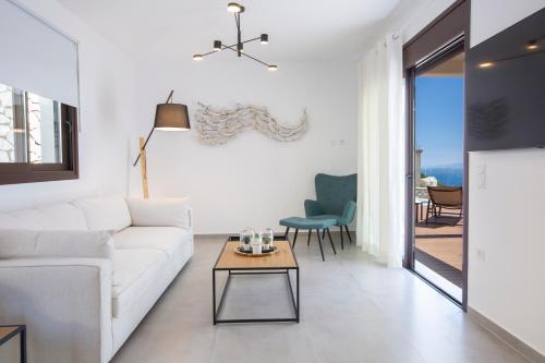 a living room with a white couch and a table at Heavenly Heights Villas By KB Hospitality in Évyiros