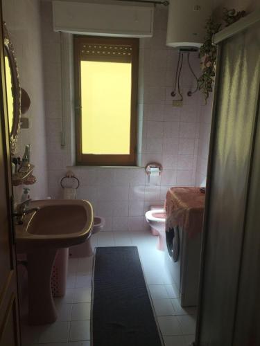 a bathroom with a sink and a toilet and a window at B&B ANNA in Piscinas
