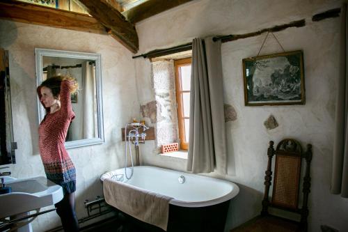 Eine Frau, die im Bad steht und aus dem Fenster schaut. in der Unterkunft La petite Maison du Bonheur & Jacuzzi 