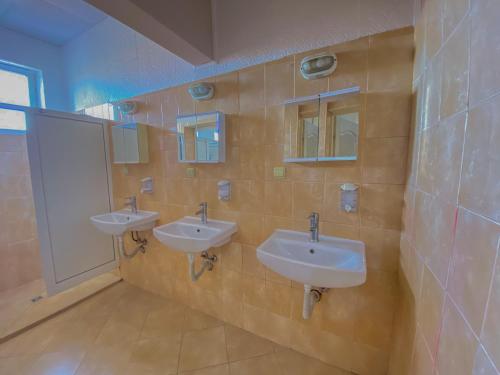 een badkamer met 3 wastafels en 2 spiegels bij Пансион - Димитър Хадживасилев in Svishtov