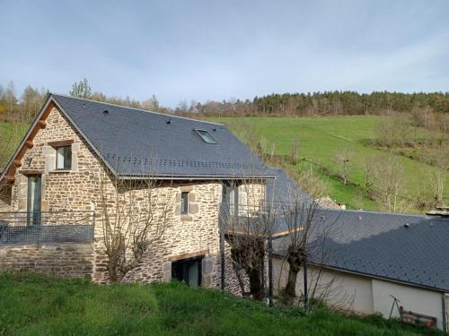 a stone house with a black roof on a hill at Le Loft in Barjac