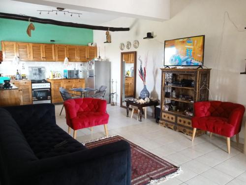 a living room with red chairs and a kitchen at Mavericks Convenient Cozy Loft in Diani's CBD in Ukunda