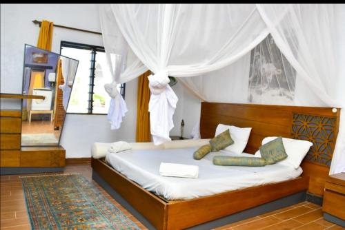 a bedroom with a large bed with a white canopy at Mavericks Convenient Cozy Loft in Diani's CBD in Ukunda