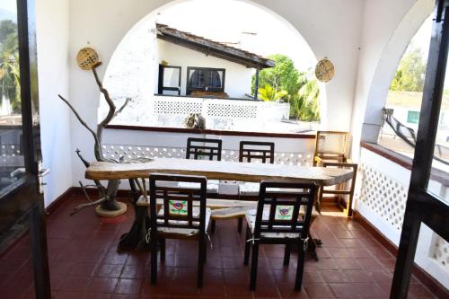 a dining room with a table and chairs on a balcony at Mavericks Convenient Cozy Loft in Diani's CBD in Ukunda