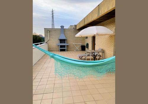 a blue hammock on a patio with an umbrella at Apartamento Familiar T3 em Valongo com Terraço Privativo e Churrasqueira in Campo