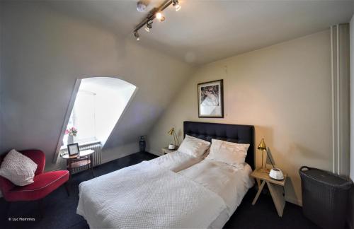 a bedroom with a large bed and a red chair at city Apartment "Op de Thermen" in Maastricht