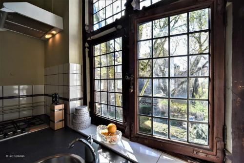 a kitchen with large windows and a sink and a counter at city Apartment "Op de Thermen" in Maastricht