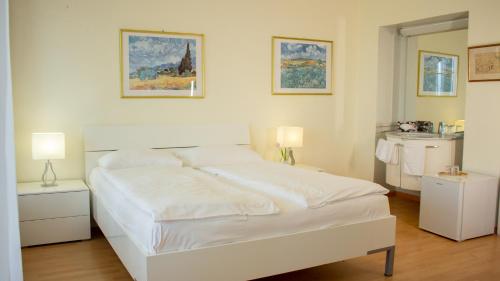 a white bed in a room with two lamps at Easy Stay by Hotel La Perla in Ascona