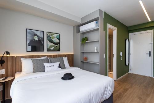 a bedroom with a white bed and a green wall at Charlie For You Vila Mariana in São Paulo