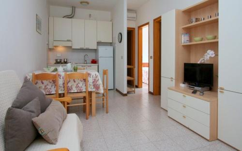 a kitchen and a living room with a couch and a tv at Villa Capinera in Lignano Sabbiadoro
