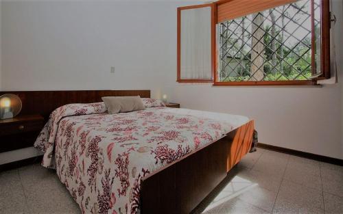 a bedroom with a bed with a red and white blanket at Villa Capinera in Lignano Sabbiadoro
