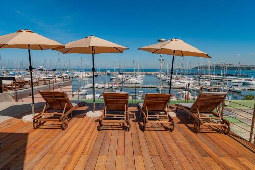 four chairs and umbrellas on a deck with a marina at L'Isola Del Postino Rooms in Procida