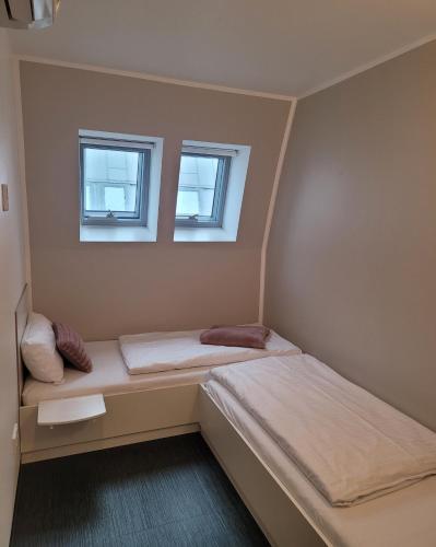 twee bedden in een kleine kamer met twee ramen bij Open-Water-Resort in Geierswalde