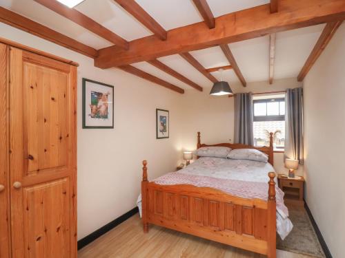 a bedroom with a wooden bed and a window at Cow Byre Cottage in Whitby