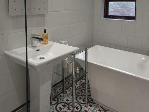 a white bathroom with a sink and a bath tub at Sgurr Mor Lodge - Smmd in Balmacara