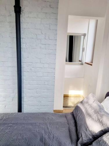 um quarto com uma cama e uma parede de tijolos brancos em Cozy apartment near city center em Bucareste