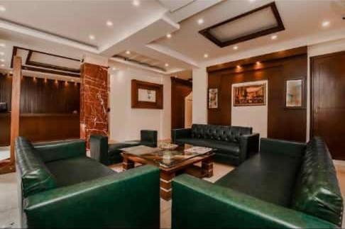 a living room with green couches and a table at Hotel Gaylord International - New Delhi in New Delhi